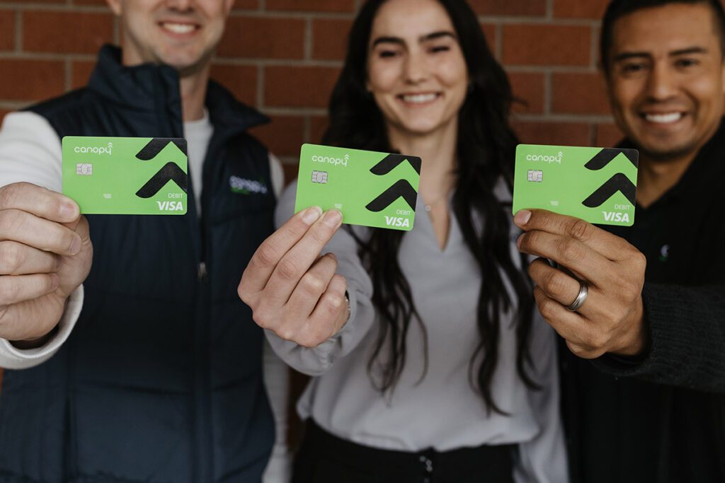 A diverse group of Canopy Credit Union members holding their visa cards.