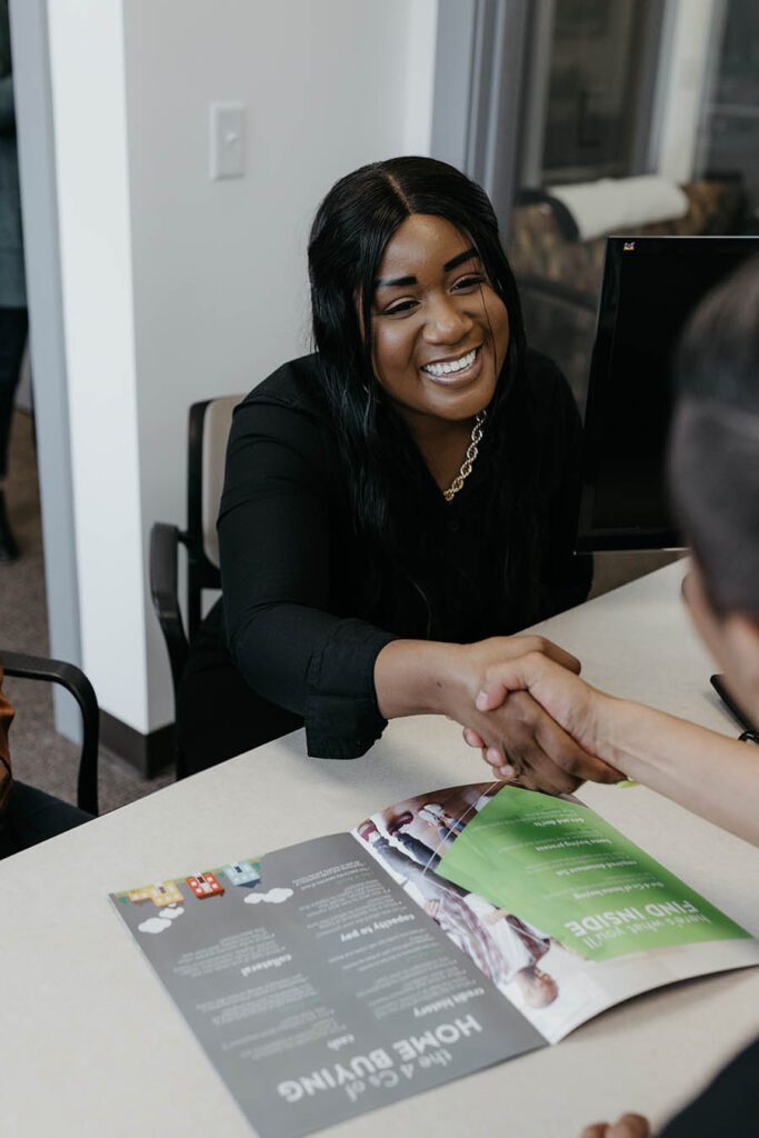 A happy first time home buyer shaking a canopy CU agent's hand.