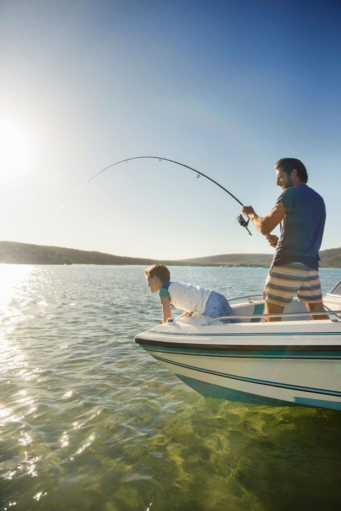 A father and son fishing off the front of their boat.