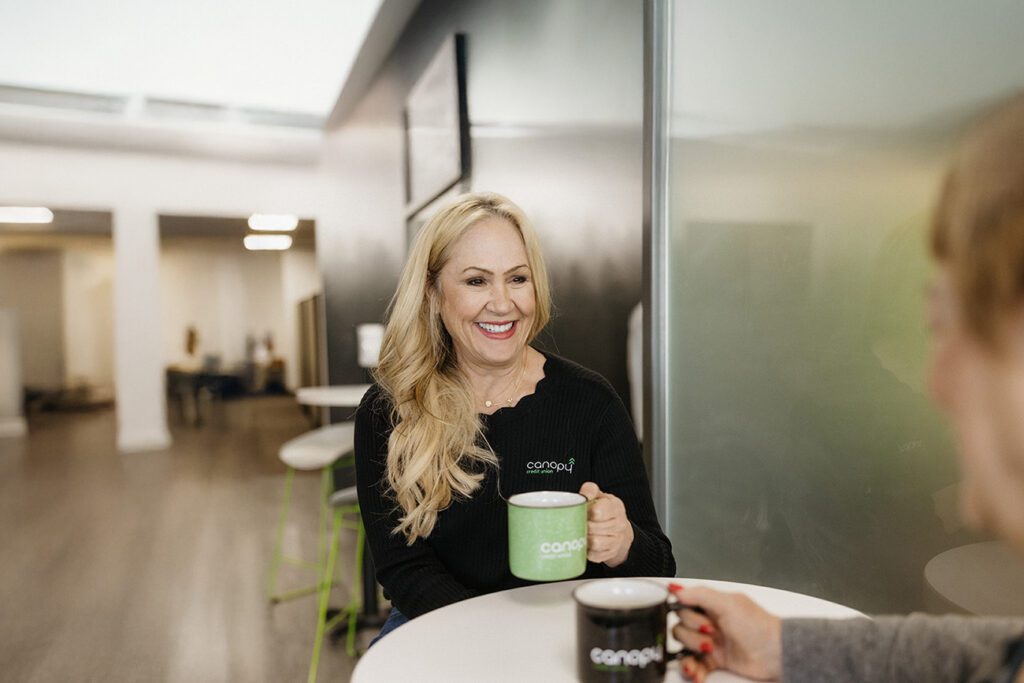 A woman chatting with a Canopy representative over coffee.
