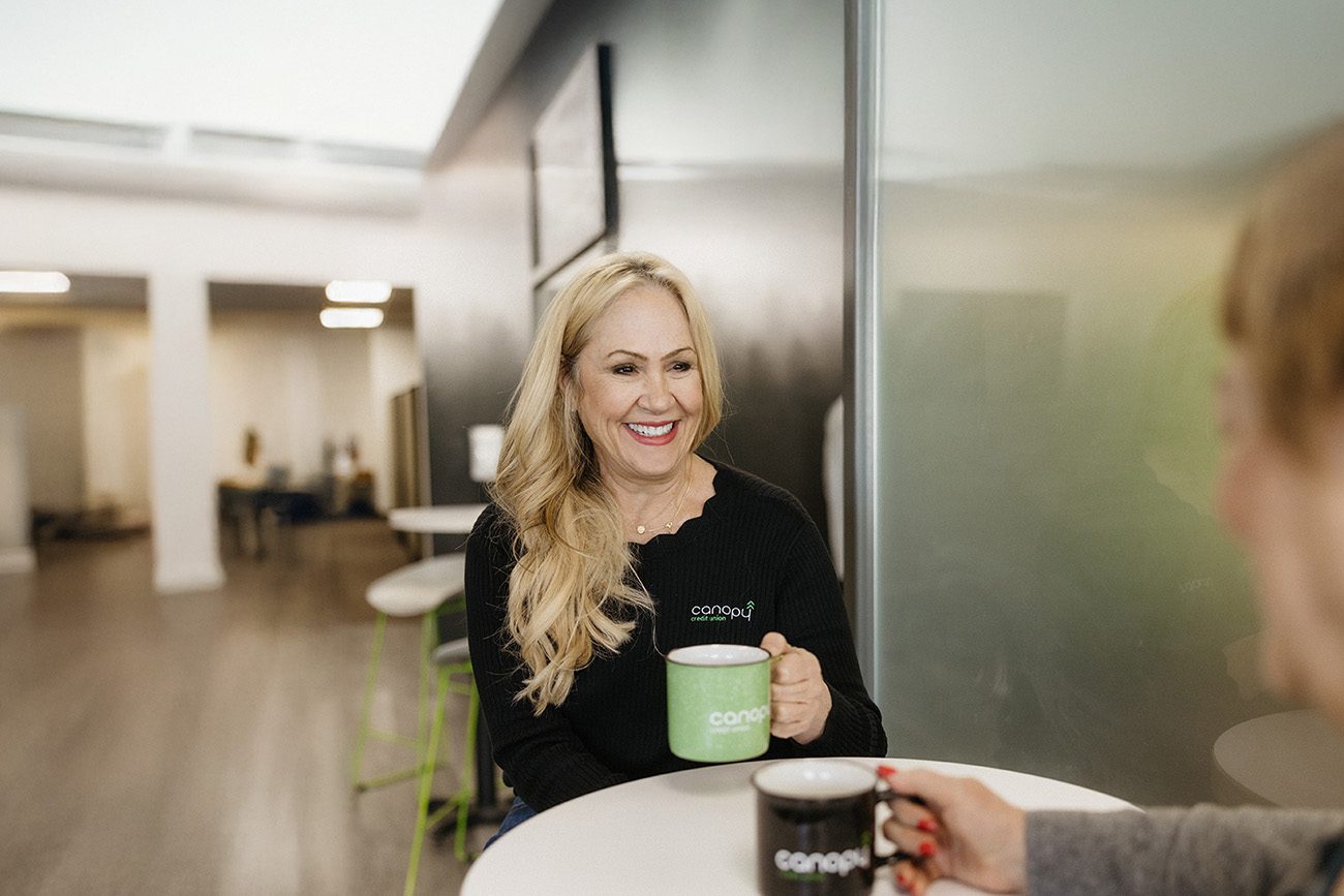 A woman chatting with a Canopy representative over coffee.