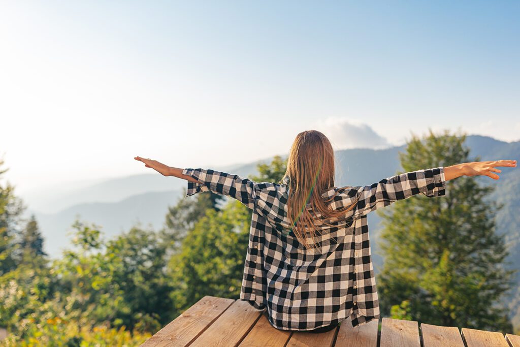 A happy young woman with her arms outstretched as if embracing the world around her.